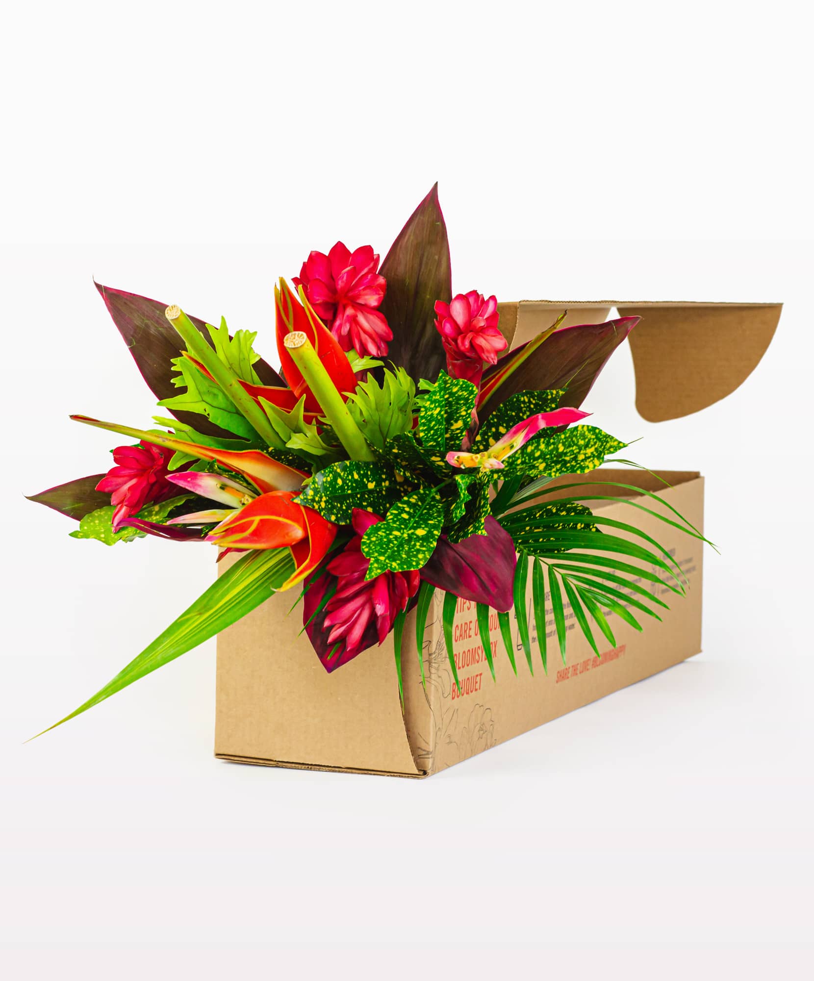 Vibrant tropical flower arrangement featuring bold reds and lush greens in a delivery box.